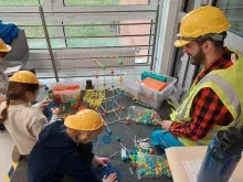 dzieci i opiekun przy stoisku budowlanym