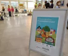 plakat "Miasteczka Przedsiębiorczości" ze stoiskami w tle